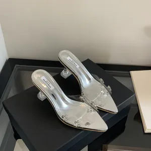 Close-up of silver pointed-toe mules with transparent straps and sparkling rhinestone accents.