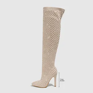 Détail de cuissardes beiges à bout pointu avec des talons aiguilles hauts de 11 cm