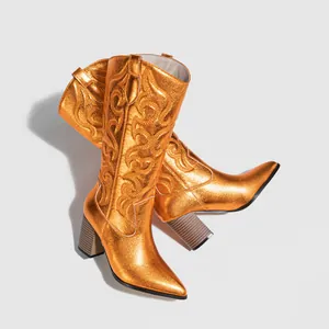 Detail view of metallic orange cowboy boots featuring intricate embroidery and a block heel
