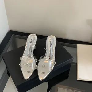 Close-up of silver pointed-toe heels with crystal rhinestones on a black box