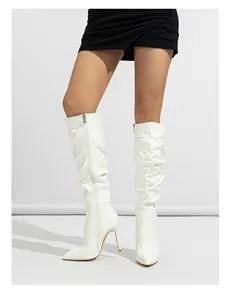 Detailed view of stylish white patent leather pleated knee-high boots with stiletto heel