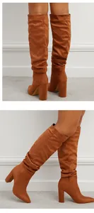 Close-up detail showing the texture of tan suede slouchy high-heeled boots with pointed toe