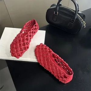 Detailed shot of red woven hollow-out flat sandals with intricate knotting.