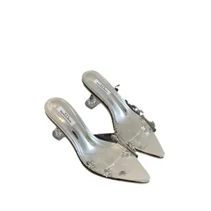 Detail view of transparent pointed-toe high heels with sparkling rhinestone embellishments