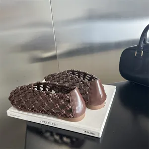 Detailed macro view of brown woven hollow flat shoes resting on a white art book