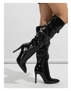 Close-up view of shiny black patent leather slouchy over-the-knee boots with stiletto heels