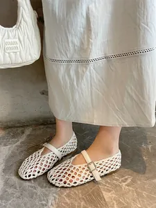 Close-up of white hand-woven hollow-out Mary Jane flat shoes with buckle strap shown on feet