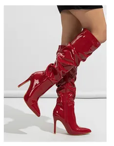 Detail of red patent leather slouchy knee-high boots with side zipper and stiletto heels