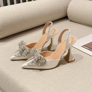 Elegante weiße Sandalen mit spitzer Zehenpartie und einer glitzernden Strassschleife