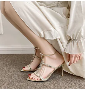 Close-up of elegant gold pointed-toe stiletto sandals with rhinestone chain details.