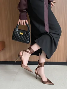 Elegantes tacones de satén marrón oscuro con punta fina y tiras para atar al tobillo.