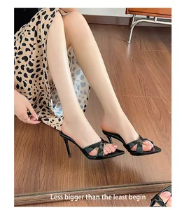 Detailed view of the elegant black patent leather pointed toe high-heeled mules on feet