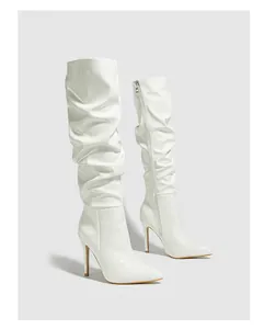 Macro view of white pleated patent leather high boots featuring a sleek stiletto heel