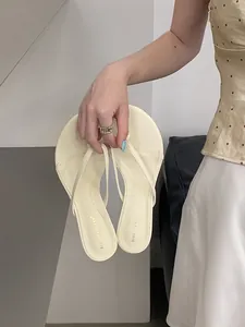 Primo piano di infradito crema minimaliste tenute in mano stile resort
