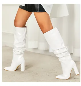 Detailed side view of white patent leather slouchy mid-calf boots featuring a chunky high heel