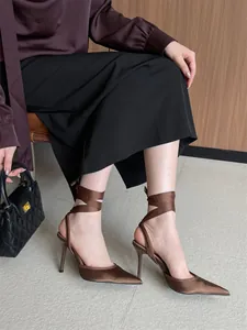 Detalle de zapatos de tacón de satén marrón con cintas elegantes para atar al tobillo.