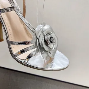 Gedetailleerd aanzicht van een elegante zilveren metallic sandaal met een grote decoratieve roos