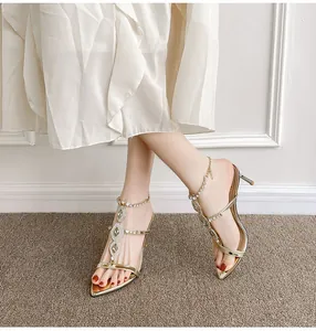 Close-up of gold stiletto sandals with sparkling rhinestone details and pointed toe.