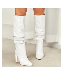 Elegant white slouchy patent leather boots featuring a pointed toe and sturdy block heel