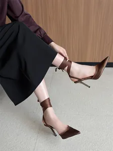 Elegantes tacones de satén marrón con punta fina y cintas de seda en los tobillos.