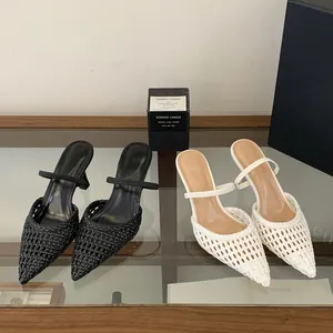 Close-up of elegant pointed-toe woven hollow-out stiletto mules in black and white