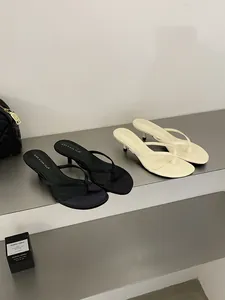 Eleganti sandali infradito con tacco gattino in nero e beige per un look estivo chic.