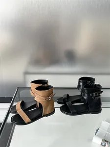 Detailed macro view of khaki and black flat gladiator sandals on a modern glass shelf