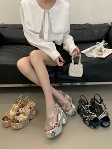 Detail view of stylish floral platform sandals with butterfly charms and high wedge heels