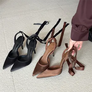 Vista detallada de elegantes tacones de punta con cintas en el tobillo en negro y marrón.