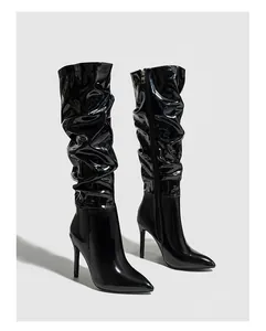 Detail of black patent leather high boots with stylish wrinkled design and stiletto heel