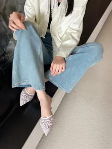 Model wearing elegant white mesh pointed-toe mules with delicate floral embroidery