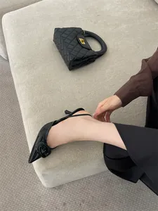 Side detail of black patent leather pointed-toe high heels featuring a stylish square buckle