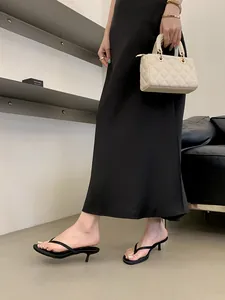 Eleganti sandali infradito neri con tacco kitten, abbinati a una gonna longuette in raso.