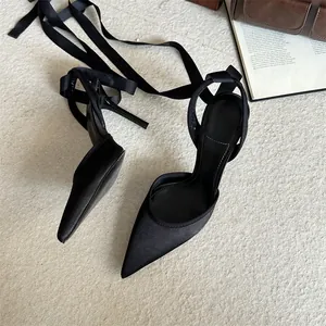 Detalle de tacones negros de punta con elegantes cintas de satén al tobillo