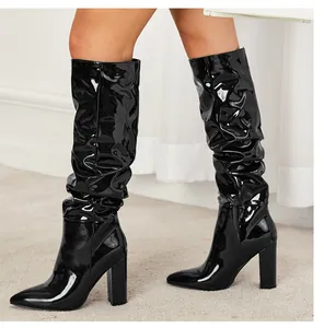 Close-up of black patent leather mid-calf slouchy boots with pointed toe and block heels.