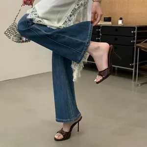 Detail of elegant dark brown patent high-heel mule sandals worn with flared jeans