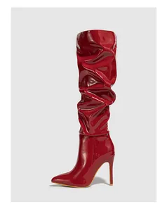 Close-up of glossy red slouchy over-the-knee boots with high stiletto heels.