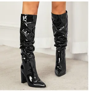 Close-up of black patent leather slouchy boots with pointed toe and chunky high heel