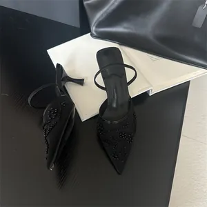 Detail of black pointed-toe kitten heel mules with elegant floral embroidery and mesh.