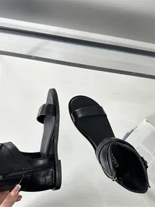 Detailed view of women's black flat Roman sandals with rear zipper and soft leather texture.