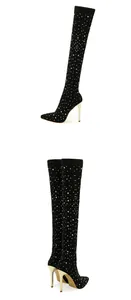 Detailed view of black rhinestone-studded over-the-knee boots with gold stiletto heels