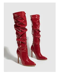 Red patent leather slouchy knee-high boots with stiletto heels and pointed toe