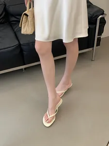 Dettaglio di sandali infradito color crema in stile francese con tacco basso su modella