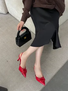 Detailed view of red pointed-toe slingback heels with decorative buckle detail