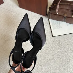 Primer plano de zapatos slingback de raso negro con elegante puntera afilada
