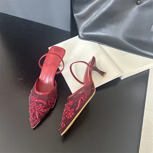 Close-up of red pointed-toe mules with elegant floral embroidery and delicate mesh details.
