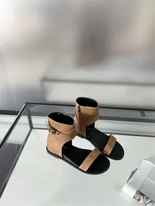 Close-up of brown flat Roman sandals with ankle strap and buckle on glass table