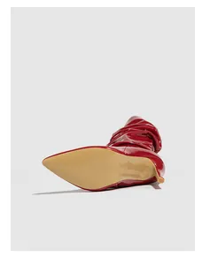Detailed view of red patent leather slouchy boots showing the smooth sole and texture