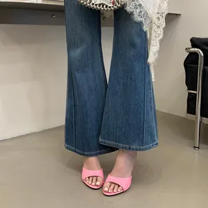 Detailed view of pink glossy peep-toe high-heeled mules paired with flared blue jeans