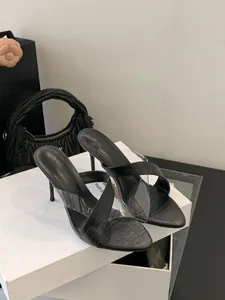 Detailansicht schwarzer Pantoletten mit Pfennigabsatz, Krokoprägung und PVC-Riemen.